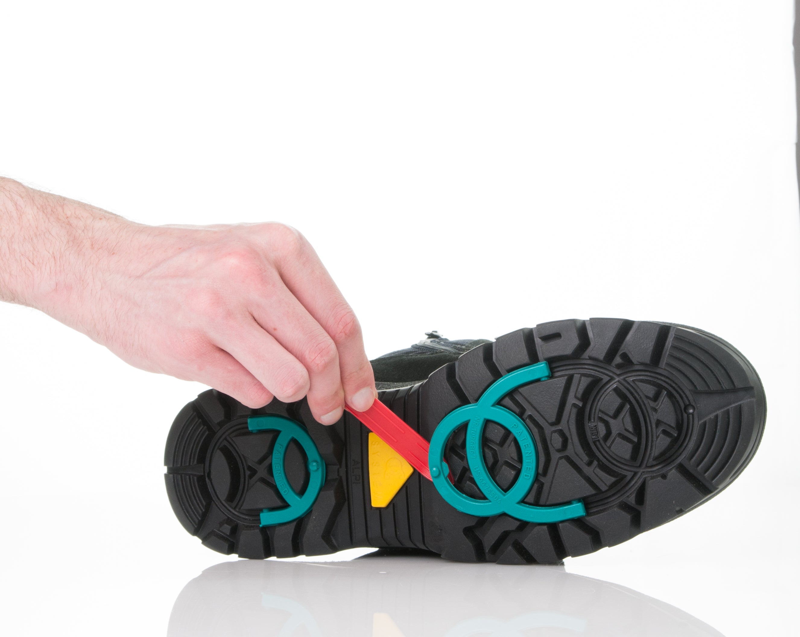 Black Attiba Eiger 2 men's boot sole with a red tab retracting the teal grip spikes, bottom view
