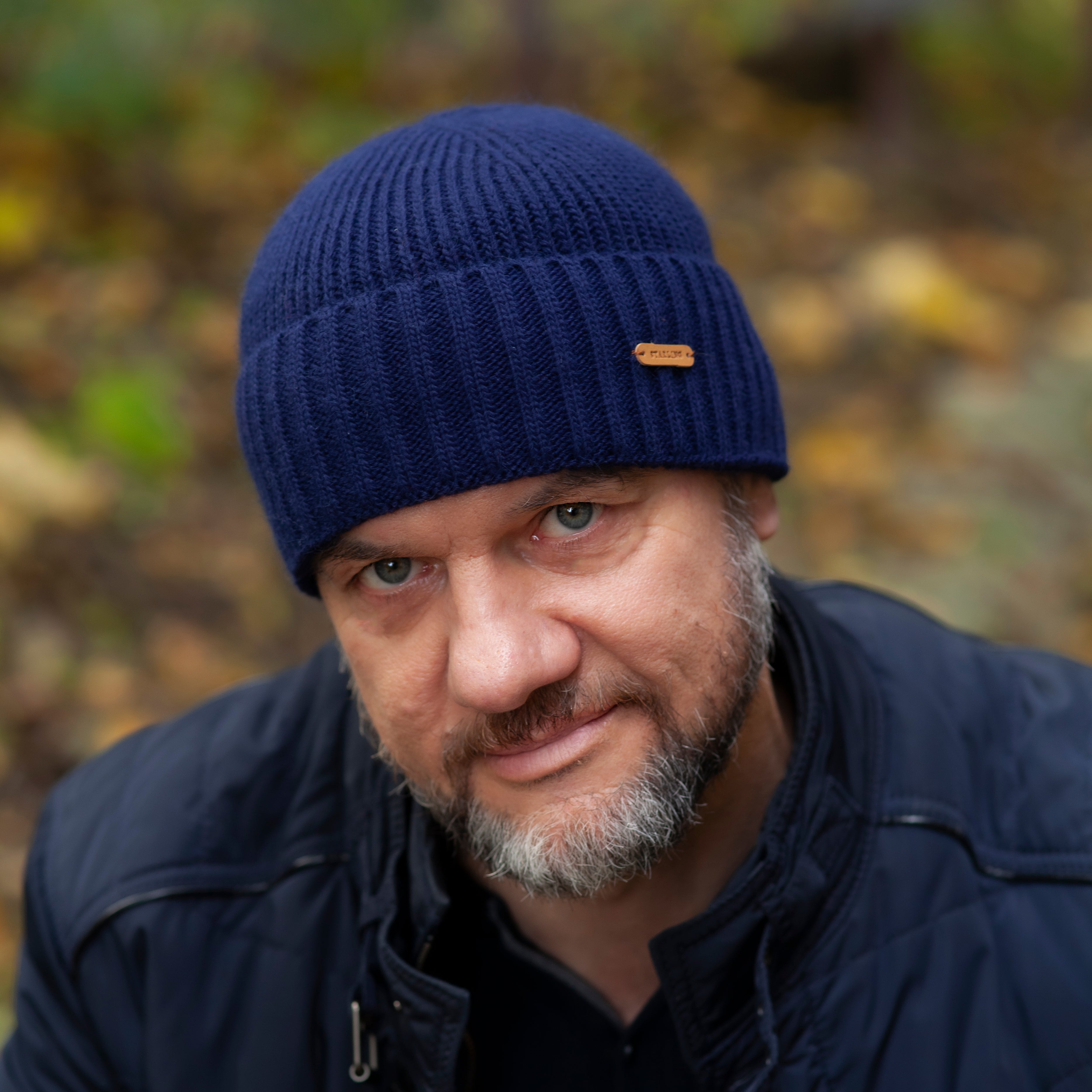 Man outdoors in a forest wearing a navy Starling Buddy ribbed wool beanie